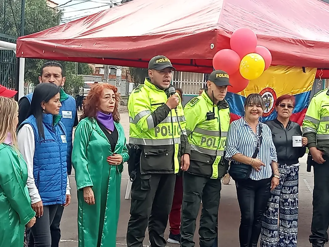 Integrantes de la fundación acompañando a la Policía Nacional en la apertura de un evento comunitario, bajo una carpa con globos y la bandera de Colombia.